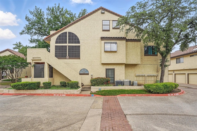 5590 Spring Valley Rd Unit C208, Dallas, TX 75254 - view of front facade featuring stucco siding, central air condition unit, and a tiled roof