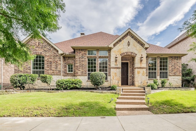 2117 Torin St, Lewisville, TX 75056 - french provincial home featuring stone siding, a front yard, roof with shingles, and brick siding
