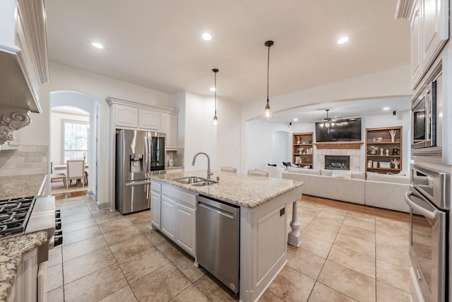 2117 Torin St, Lewisville, TX 75056 - kitchen featuring stainless steel appliances, a sink, arched walkways, a ceiling fan, and a fireplace