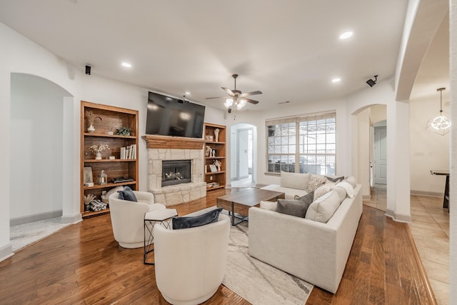 2117 Torin St, Lewisville, TX 75056 - living room featuring arched walkways, ceiling fan, a stone fireplace, baseboards, and wood finished floors