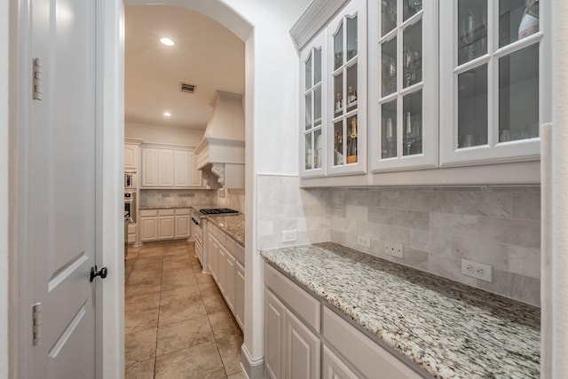 2117 Torin St, Lewisville, TX 75056 - kitchen with arched walkways, premium range hood, decorative backsplash, stainless steel appliances, and recessed lighting