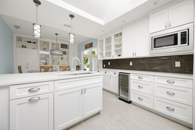 15810 Ranchita Dr, Dallas, TX 75248 - kitchen with wine cooler, a sink, stainless steel microwave, open shelves, and white cabinetry