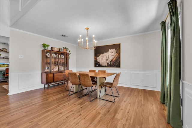 13734 Riverview Dr, Woodway, TX 76712 - dining space featuring a chandelier, light wood finished floors, crown molding, a wainscoted wall, and a decorative wall