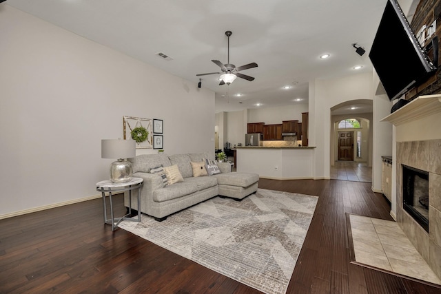 3532 Gallant Trl, Fort Worth, TX 76244 - living room with arched walkways, ceiling fan, a tiled fireplace, baseboards, and hardwood / wood-style flooring