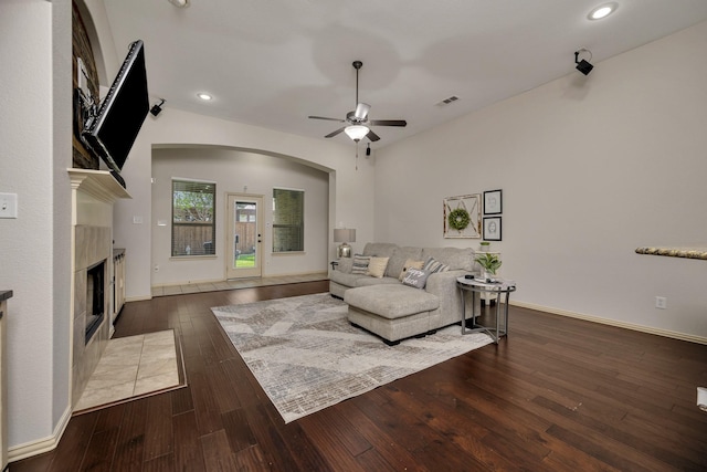 3532 Gallant Trl, Fort Worth, TX 76244 - living area featuring arched walkways, ceiling fan, a tiled fireplace, wood-type flooring, and baseboards
