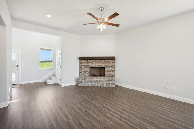 1005 Springfield Dr, Springtown, TX 76082 - unfurnished living room featuring stairway, dark wood finished floors, ceiling fan, a brick fireplace, and baseboards
