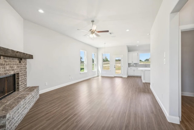 1005 Springfield Dr, Springtown, TX 76082 - unfurnished living room with ceiling fan, dark wood finished floors, baseboards, a brick fireplace, and recessed lighting