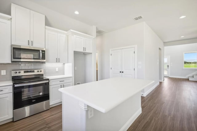 1005 Springfield Dr, Springtown, TX 76082 - kitchen featuring stainless steel appliances, dark wood-type flooring, tasteful backsplash, a kitchen island, and light countertops