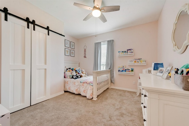 15393 Armstrong Rd, Terrell, TX 75160 - bedroom with a barn door, light carpet, a ceiling fan, and baseboards
