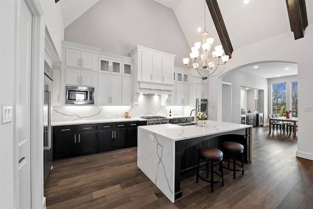 15140 Spider Lily Rd, Frisco, TX 75035 - kitchen featuring stainless steel appliances, high vaulted ceiling, arched walkways, dark cabinets, and a chandelier