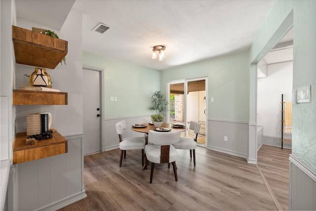 626 Pebblecreek Dr, Garland, TX 75040 - dining space with light wood-style floors and a wainscoted wall