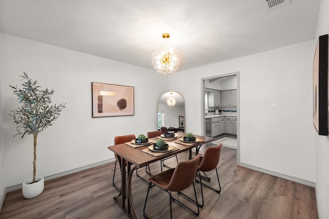 626 Pebblecreek Dr, Garland, TX 75040 - dining room featuring a chandelier, wood finished floors, arched walkways, and baseboards