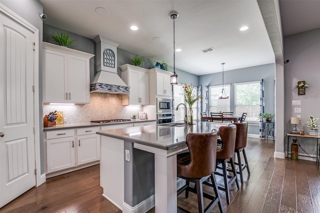 1340 Benavites Dr, Little Elm, TX 75068 - kitchen with appliances with stainless steel finishes, a center island with sink, dark wood-style floors, decorative backsplash, and a kitchen bar