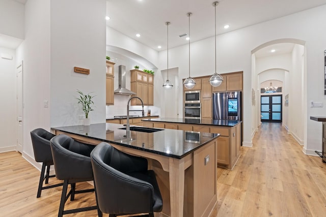 4124 Sandbrock Pkwy, Aubrey, TX 76227 - kitchen featuring stainless steel appliances, wall chimney range hood, a center island, light wood-style flooring, and a breakfast bar area