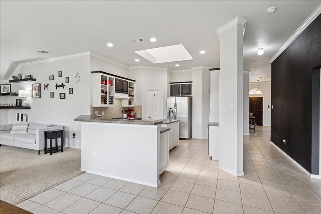 10237 Red Bluff Ln, Fort Worth, TX 76177 - kitchen with stainless steel fridge with ice dispenser, light tile patterned floors, a skylight, backsplash, and ornamental molding