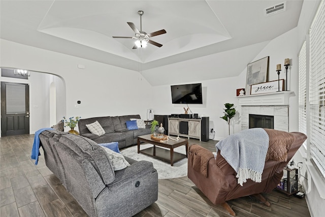 2512 Bunker Hill Dr, Burleson, TX 76028 - living room featuring a tray ceiling, ceiling fan, wood finished floors, arched walkways, and a tiled fireplace