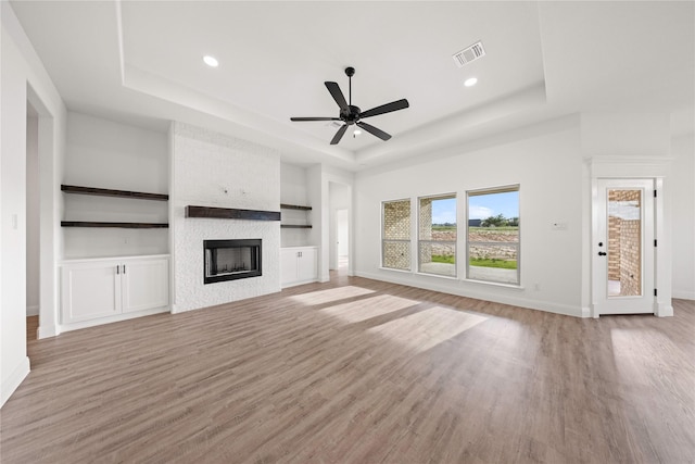 7009 Ranch View Pl, Springtown, TX 76082 - unfurnished living room featuring a tray ceiling, light wood finished floors, a fireplace, a ceiling fan, and baseboards