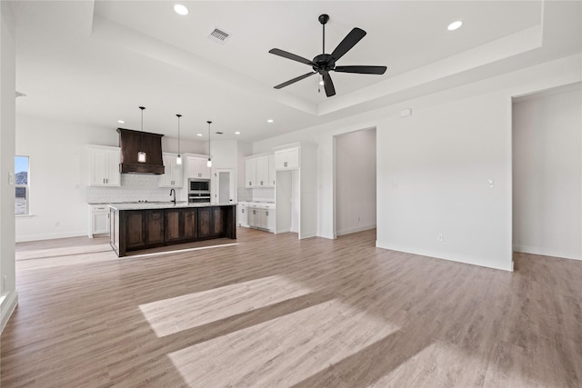 7009 Ranch View Pl, Springtown, TX 76082 - unfurnished living room with a raised ceiling, a sink, recessed lighting, ceiling fan, and light wood-style floors