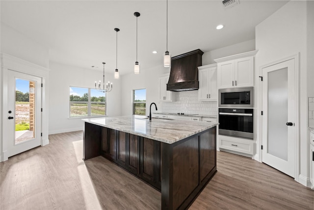 7009 Ranch View Pl, Springtown, TX 76082 - kitchen featuring wall oven, custom range hood, stainless steel microwave, a sink, and light wood-type flooring