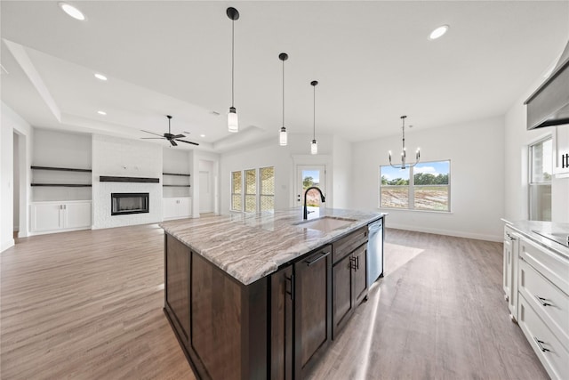 7009 Ranch View Pl, Springtown, TX 76082 - kitchen with a sink, ceiling fan, light wood-style floors, a large fireplace, and dark brown cabinetry