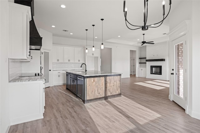 7009 Ranch View Pl, Springtown, TX 76082 - kitchen with a sink, backsplash, a large fireplace, light wood finished floors, and an island with sink