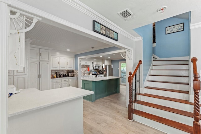 427 Paddy St, Mesquite, TX 75149 - kitchen with appliances with stainless steel finishes, white cabinetry, crown molding, light wood finished floors, and backsplash