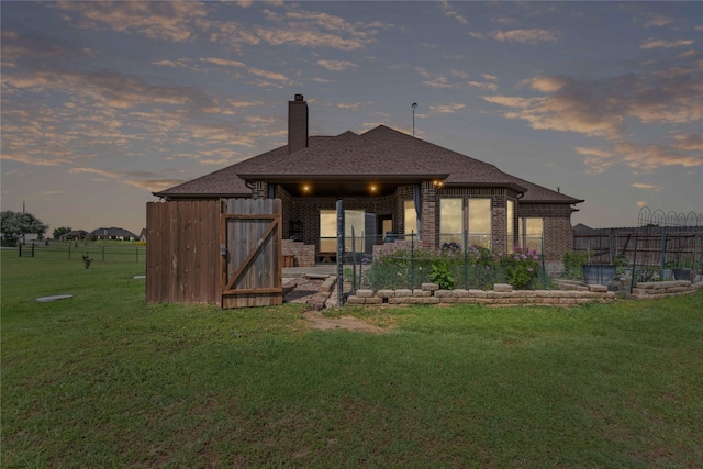 136 Spring Meadow Dr, Springtown, TX 76082 - back of house at dusk with a chimney, brick siding, and roof with shingles