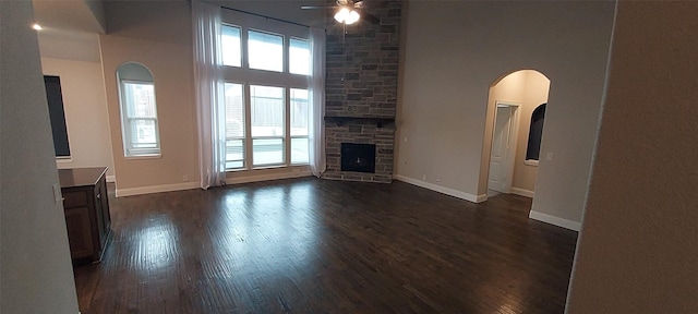 1094 Canterbury Ln, Forney, TX 75126 - unfurnished living room featuring a ceiling fan, dark wood-type flooring, a fireplace, baseboards, and a high ceiling