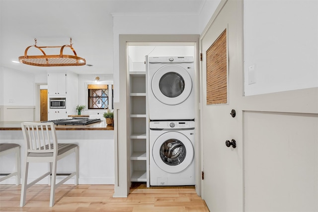 2607 Glendale Dr, Waco, TX 76710 - laundry area featuring estacked washer and dryer, light wood-style flooring, and ornamental molding