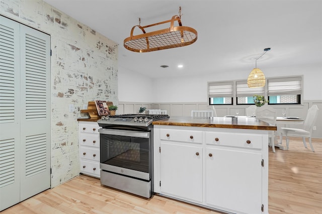 2607 Glendale Dr, Waco, TX 76710 - kitchen with stainless steel range with gas stovetop, light wood-type flooring, white cabinetry, a wainscoted wall, and dark countertops