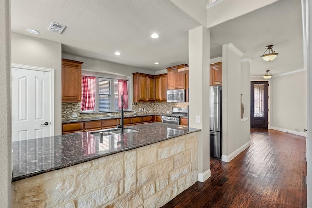 952 Tara Dr, Burleson, TX 76028 - kitchen featuring appliances with stainless steel finishes, a sink, decorative backsplash, brown cabinets, and dark wood-style flooring