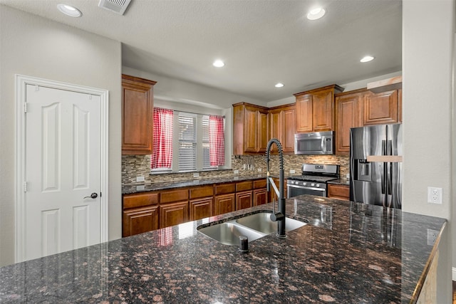 952 Tara Dr, Burleson, TX 76028 - kitchen with stainless steel appliances, a sink, tasteful backsplash, brown cabinets, and recessed lighting