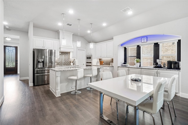 558 Lily St, Crowley, TX 76036 - kitchen featuring stainless steel appliances, premium range hood, white cabinets, tasteful backsplash, and a kitchen island with sink