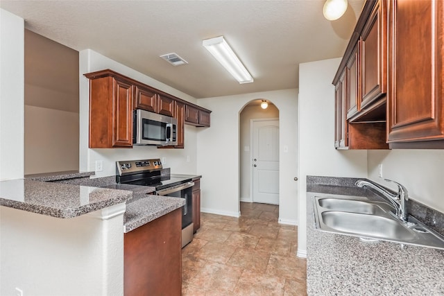 7660 Hollow Forest Dr, Fort Worth, TX 76123 - kitchen with appliances with stainless steel finishes, a sink, arched walkways, a peninsula, and baseboards