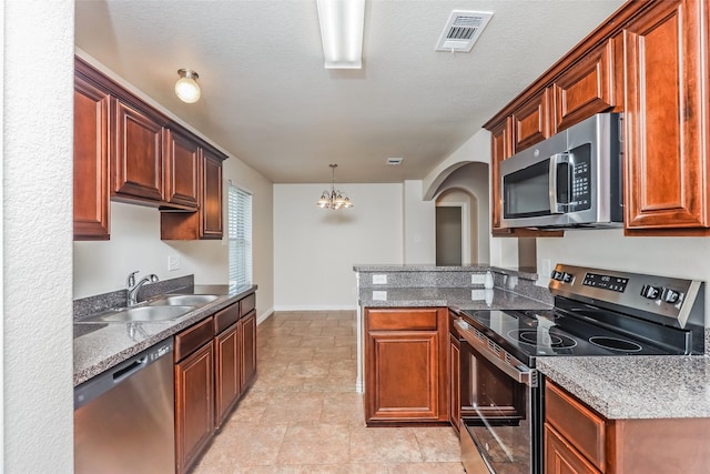 7660 Hollow Forest Dr, Fort Worth, TX 76123 - kitchen with stainless steel appliances, a sink, baseboards, a peninsula, and a chandelier
