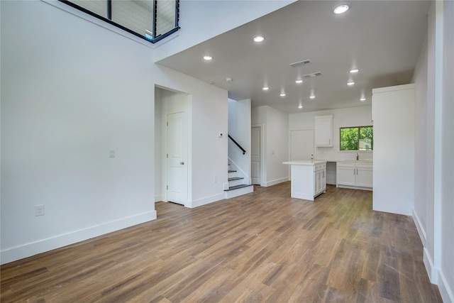 312 Beckham St, Sulphur Springs, TX 75482 - unfurnished living room featuring stairway, baseboards, wood finished floors, recessed lighting, and a sink