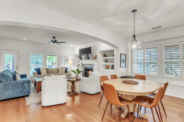 2081 Ashbourne Dr, Rockwall, TX 75087 - dining room with a warm lit fireplace, light wood-style floors, a ceiling fan, and recessed lighting