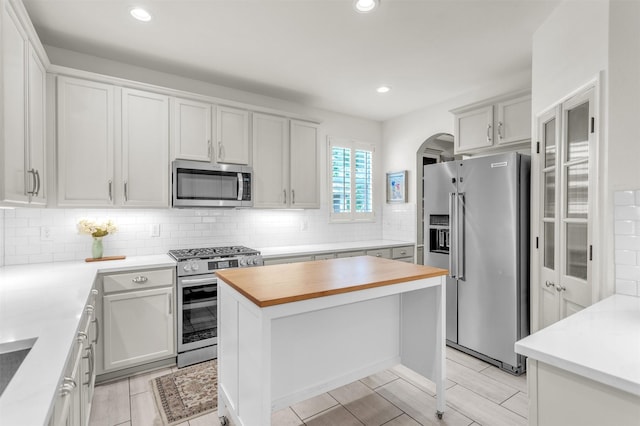 2081 Ashbourne Dr, Rockwall, TX 75087 - kitchen with appliances with stainless steel finishes, wood counters, tasteful backsplash, arched walkways, and recessed lighting