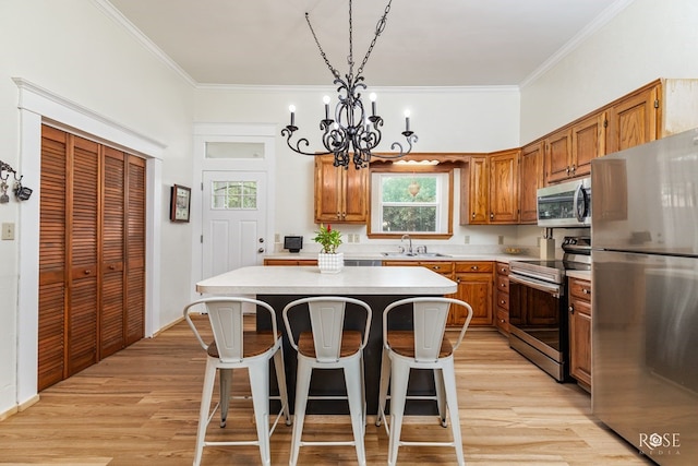 112 5th Ave, Coleman, TX 76834 - kitchen with appliances with stainless steel finishes, a chandelier, a center island, crown molding, and a kitchen breakfast bar