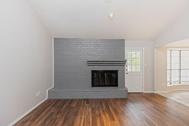 2109 Dartmouth Dr, Arlington, TX 76015 - unfurnished living room with wood finished floors, a brick fireplace, baseboards, and lofted ceiling