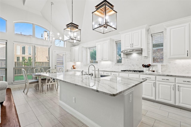 7224 Bucanero, Grand Prairie, TX 75054 - kitchen featuring a sink, a chandelier, tasteful backsplash, light stone counters, and white cabinetry