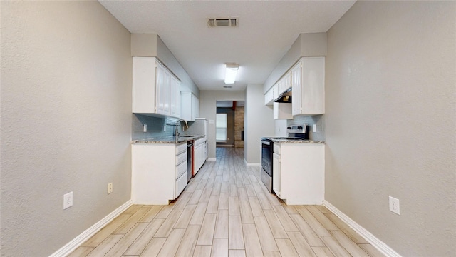 928 Thistle Ridge Ln, Arlington, TX 76017 - kitchen featuring stainless steel appliances, backsplash, light wood-style floors, white cabinets, and a textured wall