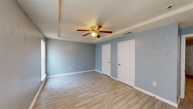 928 Thistle Ridge Ln, Arlington, TX 76017 - unfurnished bedroom featuring a textured ceiling, baseboards, light wood-style flooring, and a raised ceiling