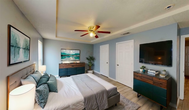 928 Thistle Ridge Ln, Arlington, TX 76017 - bedroom with a tray ceiling, light wood-type flooring, ceiling fan, baseboards, and two closets