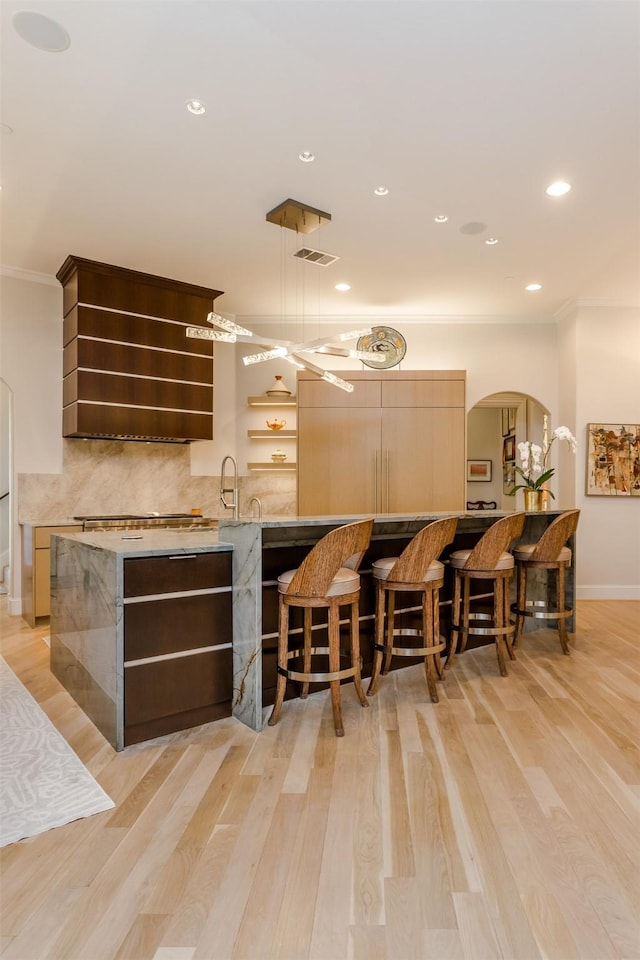 6406 Glendora Ave, Dallas, TX 75230 - bar area with arched walkways, ornamental molding, decorative backsplash, light wood finished floors, and recessed lighting
