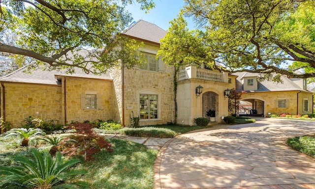 6406 Glendora Ave, Dallas, TX 75230 - view of front of property featuring stone siding, a balcony, and concrete driveway