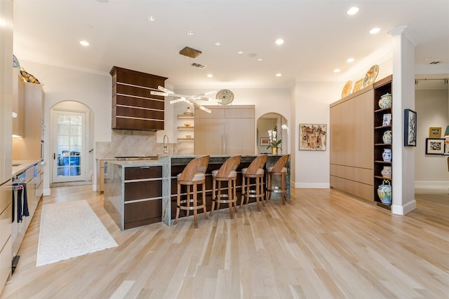 6406 Glendora Ave, Dallas, TX 75230 - kitchen with open shelves, arched walkways, crown molding, tasteful backsplash, and a kitchen breakfast bar