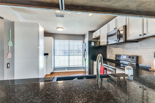 3808 River Birch Rd, Fort Worth, TX 76137 - kitchen with stainless steel microwave, electric range, freestanding refrigerator, decorative backsplash, and white cabinetry