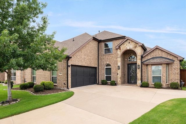 2604 Grand Colonial St, Grand Prairie, TX 75054 - french country inspired facade featuring driveway, a garage, brick siding, a front lawn, and roof with shingles
