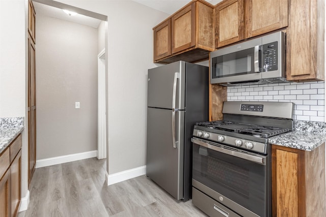 322 E Division St, Muenster, TX 76252 - kitchen featuring appliances with stainless steel finishes, light wood-style floors, brown cabinetry, and decorative backsplash